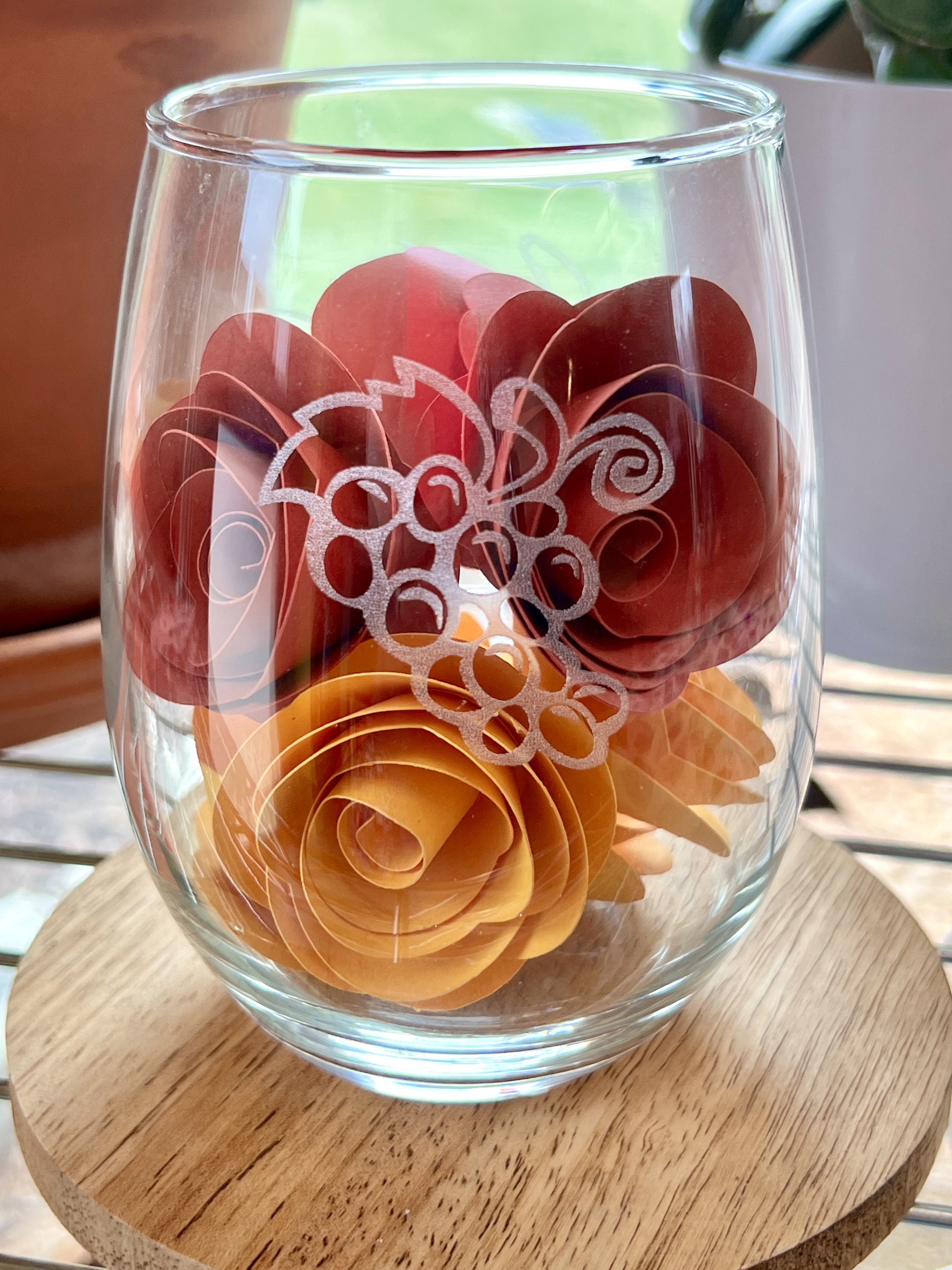 Glass tumbler with grapes etched into the glass. Glass is filled with yellow and red paper flowers.