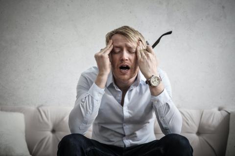 Man with headache holding temples