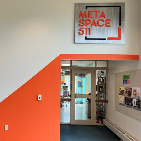 Picture of outside of MetaSpace 511 showing sign on wall that says MetaSpace 511 on beige wall with orange accents