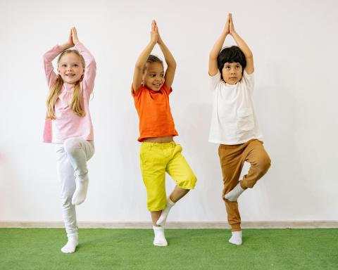 Three children doing yoga tree pose.