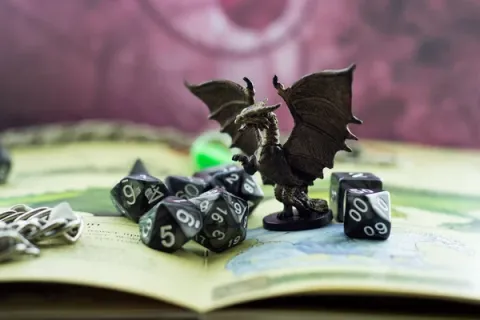 Image shows dragon figurine surrounded by dice.