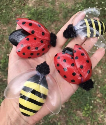 picture of hand holding two ladybugs and two bees made out of spoons