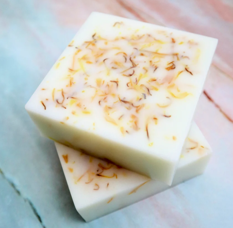 two square bars of cream colored handmade soap with flower petals in them