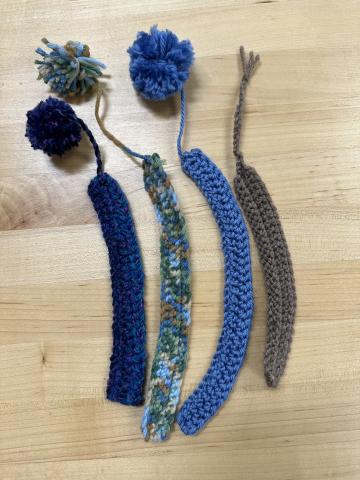 four crocheted bookmarks with pom-poms