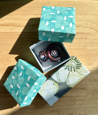 three origami gift boxes, 2 square and blue and one rectangular with scrapbook paper