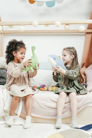 Two young girls playing with stuffed animals.