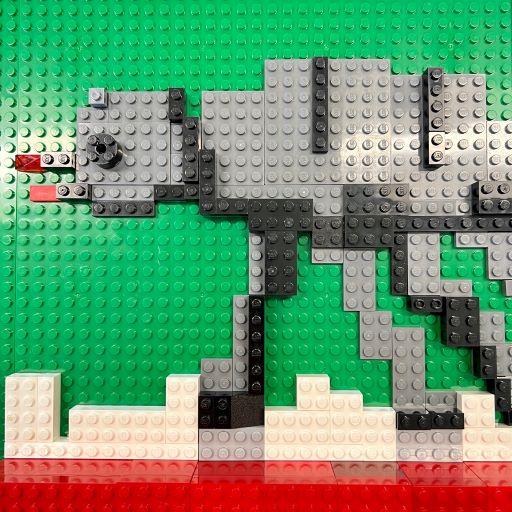 Green LEGO plate with red, white, gray, and black LEGO bricks making the image of a Star Wars AT-AT