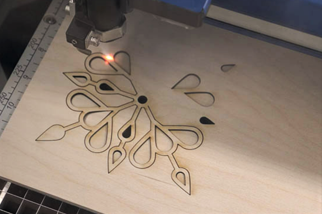 laser machine cutting out a snowflake pattern in wood