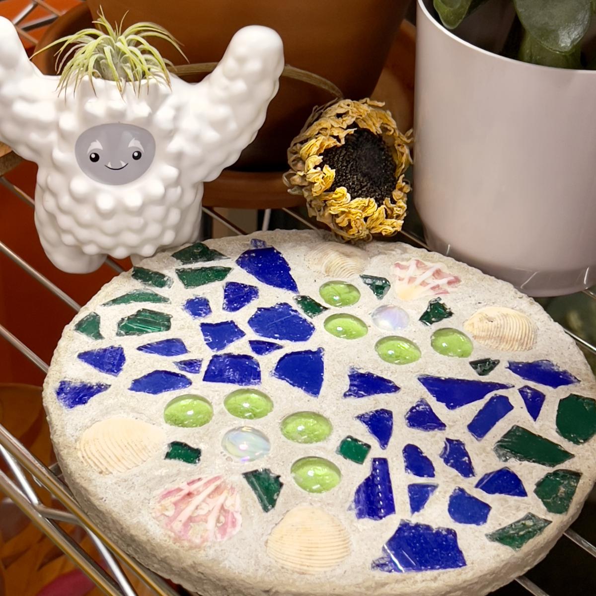 round concrete stepping stone with blue and green glass and sea shells