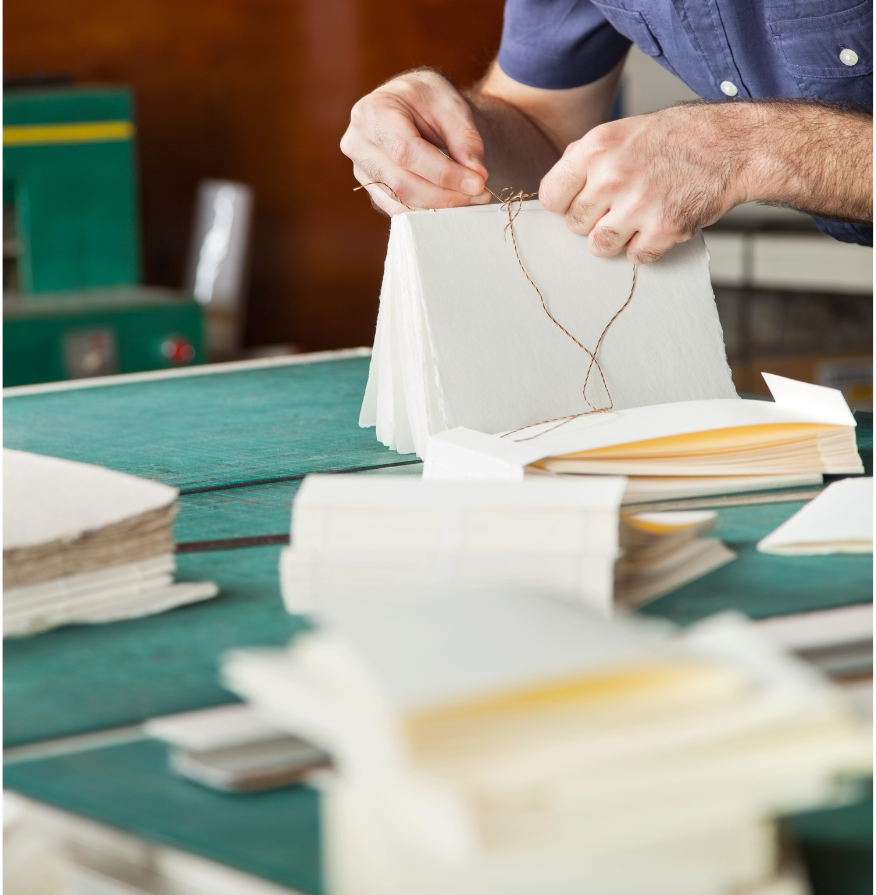 picture of hands binding a book with pages on the table